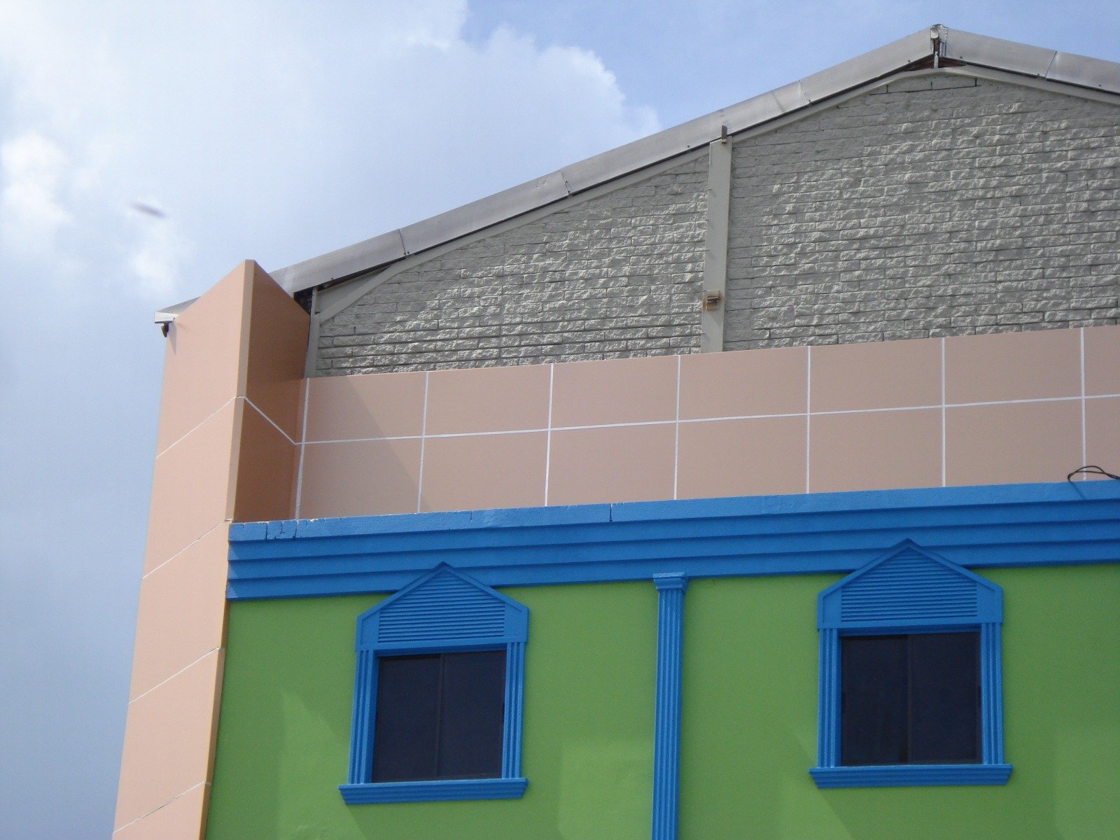 Peach aluminium composite panel parapet wall above a painted masonry building